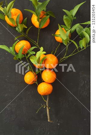 Orange tangerines with green leaves on a black background 131203454