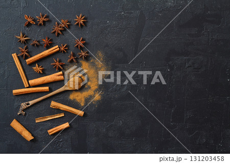 Aromatic cinnamon sticks, cinnamon powder and anise on black table, flat lay. Space for text Aromatic cinnamon sticks, cinnamon powder and anise on black table, flat lay. Space for text 131203458
