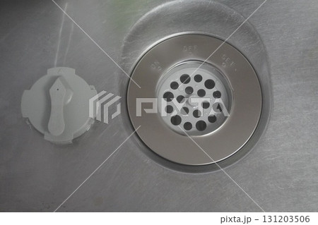 ステンレス製のキッチンシンクにある排水口とゴミ受け部分の清潔で衛生的なクローズアップ写真 131203506