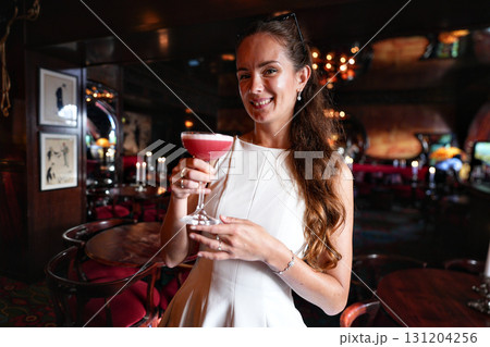 Smiling woman holding cocktail in stylish bar interior Smiling woman holding cocktail in stylish bar interior 131204256