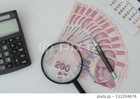 Turksh Lira banknotes of various color, pattern and value on white background. with magnifying glass 131204676