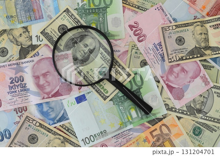 Banknotes spread out on a table with a calculator and a magnifying glass. 131204701