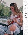 A young woman enjoys playing a ukulele outdoors, expressing joy and creativity in a serene environment. 131204811