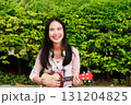 Joyful girl playing ukulele outdoors, radiating happiness in a lush green environment. 131204825
