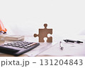Creative workspace with puzzle piece, calculator, and pens, symbolizing problem-solving and teamwork in business. 131204843
