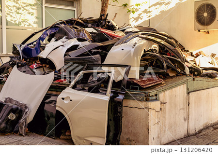 Pile of dismantled car parts and vehicle fragments stacked outdoors by building wall. Concept of car recycling, vehicle waste and auto industry, environmental concerns, automotive waste Pile of dismantled car parts and vehicle fragments stacked outdoors by building wall. Concept of car recycling, vehicle waste and auto industry, environmental concerns, automotive waste 131206420