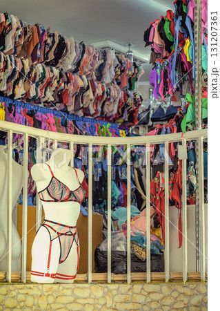 Lingerie mannequin displayed in front of crowded wall of colorful bras and panties inside fashion retail store. Concept of body positivity, female fashion, intimate diversity 131207361