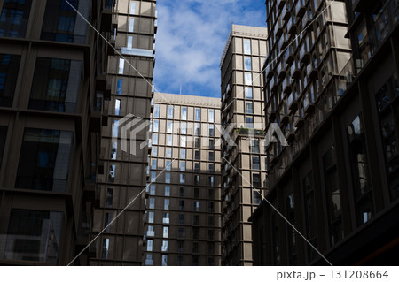 Modern residential buildings with sleek design and large windows, showcasing contemporary architecture. The structures create geometric urban aesthetic under bright sky 131208664