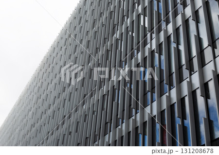 Close up of modern building facade with sleek vertical panels and windows. The design emphasizes clean lines and geometric precision, reflecting light and offering a dynamic urban look 131208678
