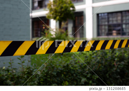 Urban scene featuring black and yellow caution tape with backdrop of modern building. This image symbolizes restricted area in city setting, blending urban life with safety measures 131208685
