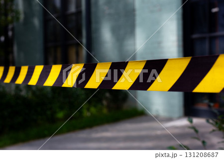 Close up of caution tape marking crime scene. The yellow and black stripes emphasize the restricted area, creating clear boundary around the scene, ideal for news stories about crime investigation 131208687