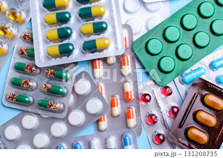 Different tablets, pills in foil blister packs, medications drugs on blue background Different tablets, pills in foil blister packs, medications drugs on blue background 131208735
