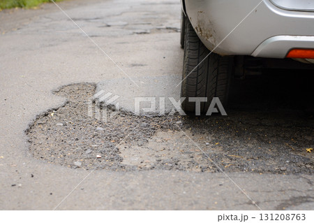 Rear wheel of a car moving through many potholes on bad road 131208763