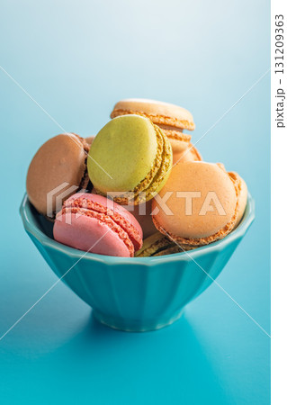 Different flavors of macarons. Colourful macaroons in bowl on blue background. 131209363