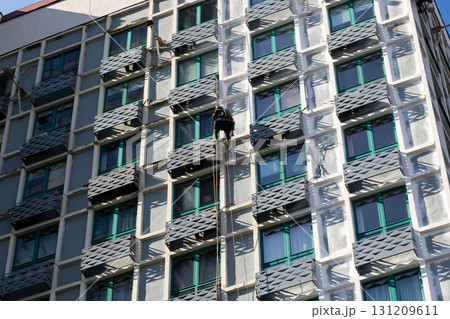 A man is currently in the process of climbing up the side of a building 131209611
