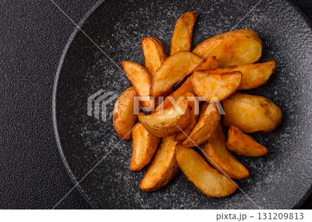 Grilled potato wedges with rosemary, cheese, salt and spices. Baked potato slices Grilled potato wedges with rosemary, cheese, salt and spices. Baked potato slices 131209813