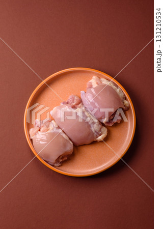 Raw chicken thigh fillet without skin and bone with salt and spices. Raw chicken fillet for cooking Raw chicken thigh fillet without skin and bone with salt and spices. Raw chicken fillet for cooking 131210534