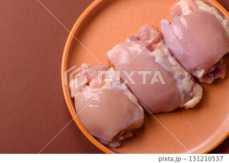 Raw chicken thigh fillet without skin and bone with salt and spices. Raw chicken fillet for cooking Raw chicken thigh fillet without skin and bone with salt and spices. Raw chicken fillet for cooking 131210537