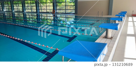 A modern indoor pool with marked lanes and starting blocks. Ideal for sports training, fitness, and swimming competitions. A modern indoor pool with marked lanes and starting blocks. Ideal for sports training, fitness, and swimming competitions. 131210689