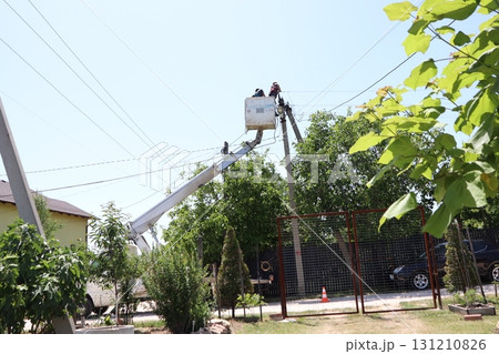 Dedicated workers are diligently repairing power lines in a busy residential area today 131210826