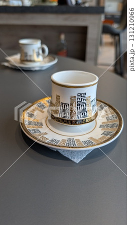 An Elegant Coffee Cup beautifully placed on a Table alongside a Decorative Saucer An Elegant Coffee Cup beautifully placed on a Table alongside a Decorative Saucer 131210966
