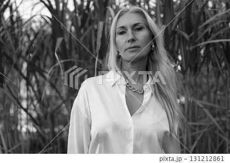 Woman in white shirt stands confidently among tall grass during golden hour Woman in white shirt stands confidently among tall grass during golden hour 131212861