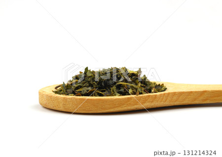 Green tea with herbs in wooden spoons on a White Background. Green tea with herbs in wooden spoons on a White Background. 131214324