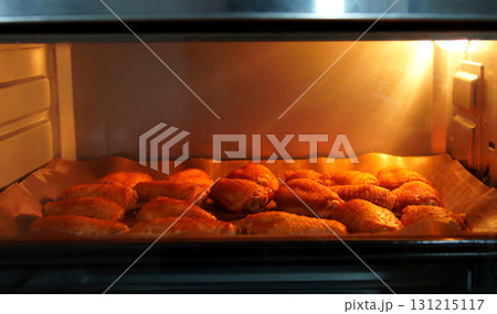 Cooking chicken wings roasted in the oven Illuminated by an orange light in the kitchen, it looks crisp and delicious. 131215117