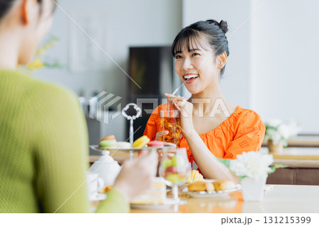 カフェでアフタヌーンティーを楽しむ若い女性 131215399