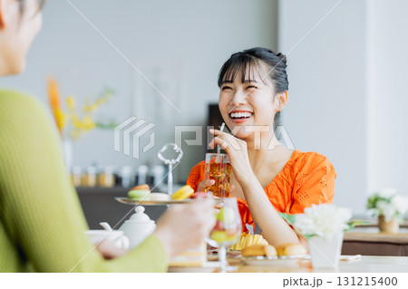 カフェでアフタヌーンティーを楽しむ若い女性 131215400