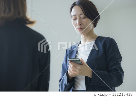 スマホを操作するスーツの女性 131215419