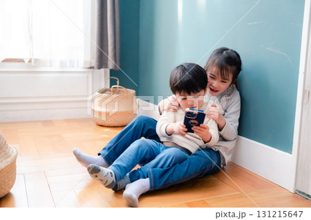 兄弟でスマホを取り合う小さな子ども 131215647