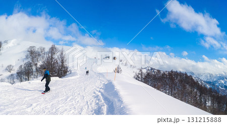 スキー場山頂付近のコースを滑るスノーボーダーと雪山のパノラマ (新潟県、南魚沼市、舞子) 131215888