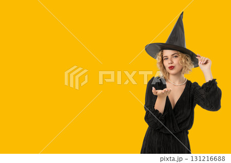 A festive witch blows kisses while wearing a black dress and hat A festive witch blows kisses while wearing a black dress and hat 131216688