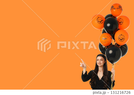 A woman holds several Halloween-themed balloons while pointing A woman holds several Halloween-themed balloons while pointing 131216726