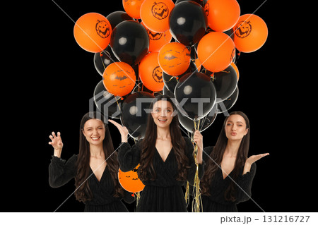 Woman dressed in black holds Halloween balloons with joy 131216727