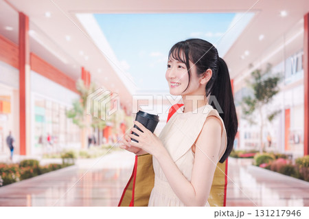 コーヒーを飲みながらショッピングモールで買い物をする女性 131217946