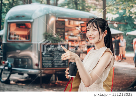 屋外のマーケットプレイスで飲食を楽しむ若い女性 屋外のマーケットプレイスで飲食を楽しむ若い女性 131218022