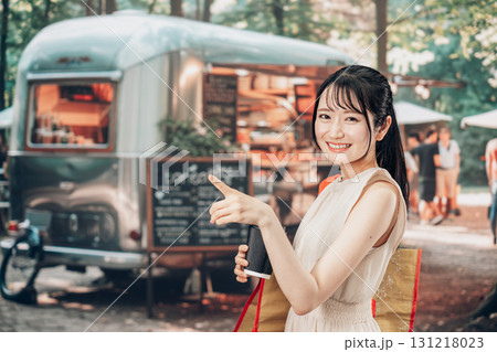 屋外のマーケットプレイスで飲食を楽しむ若い女性 131218023