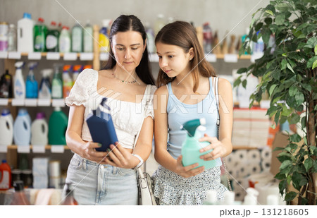 Woman with preteen girl choosing cleaning spray in household store 131218605
