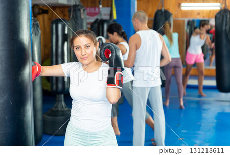 Young Latina in boxing gloves mastering punches on punching bag 131218611