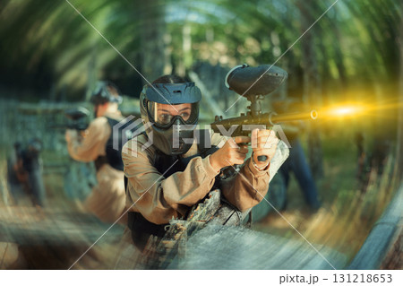 Young woman paintball player shooting with paintball marker Young woman paintball player shooting with paintball marker 131218653