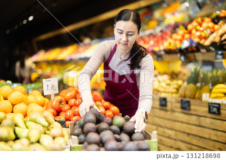 Female salesperson carefully places ripe passion fruit on the counter of grocery supermarket Female salesperson carefully places ripe passion fruit on the counter of grocery supermarket 131218698