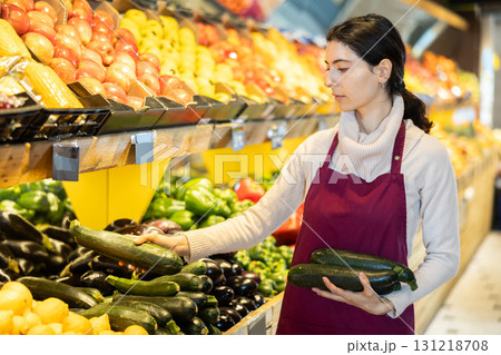 seller puts cucumbers on a shelf in a store 131218708
