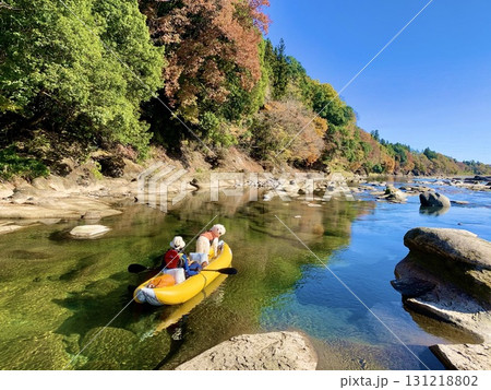 紅葉のピークを迎えた清流をカヌーで下る飼い主と白い大型犬 131218802