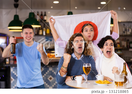 Group of happy fans celebrate victory of their favorite team with flag of Japan in beer bar 131218865