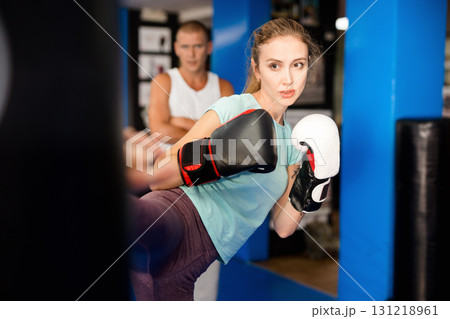 Woman kicking punchbag Woman kicking punchbag 131218961