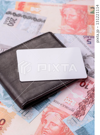 The white plastic card as a symbol of cashless payments on the background of cash paper money of Brazil 131221114