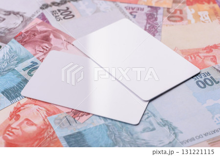 The white plastic card as a symbol of cashless payments on the background of cash paper money of Brazil 131221115