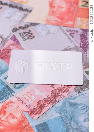 The white plastic card as a symbol of cashless payments on the background of cash paper money of Brazil The white plastic card as a symbol of cashless payments on the background of cash paper money of Brazil 131221122